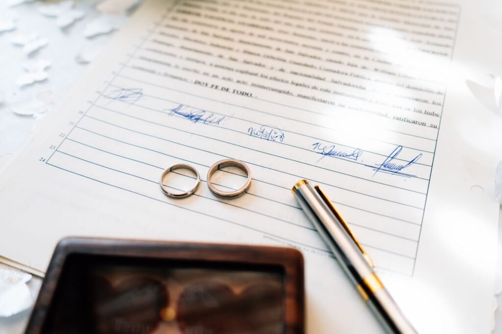 Elegant wedding rings laid on a signed marriage certificate, symbolizing commitment.