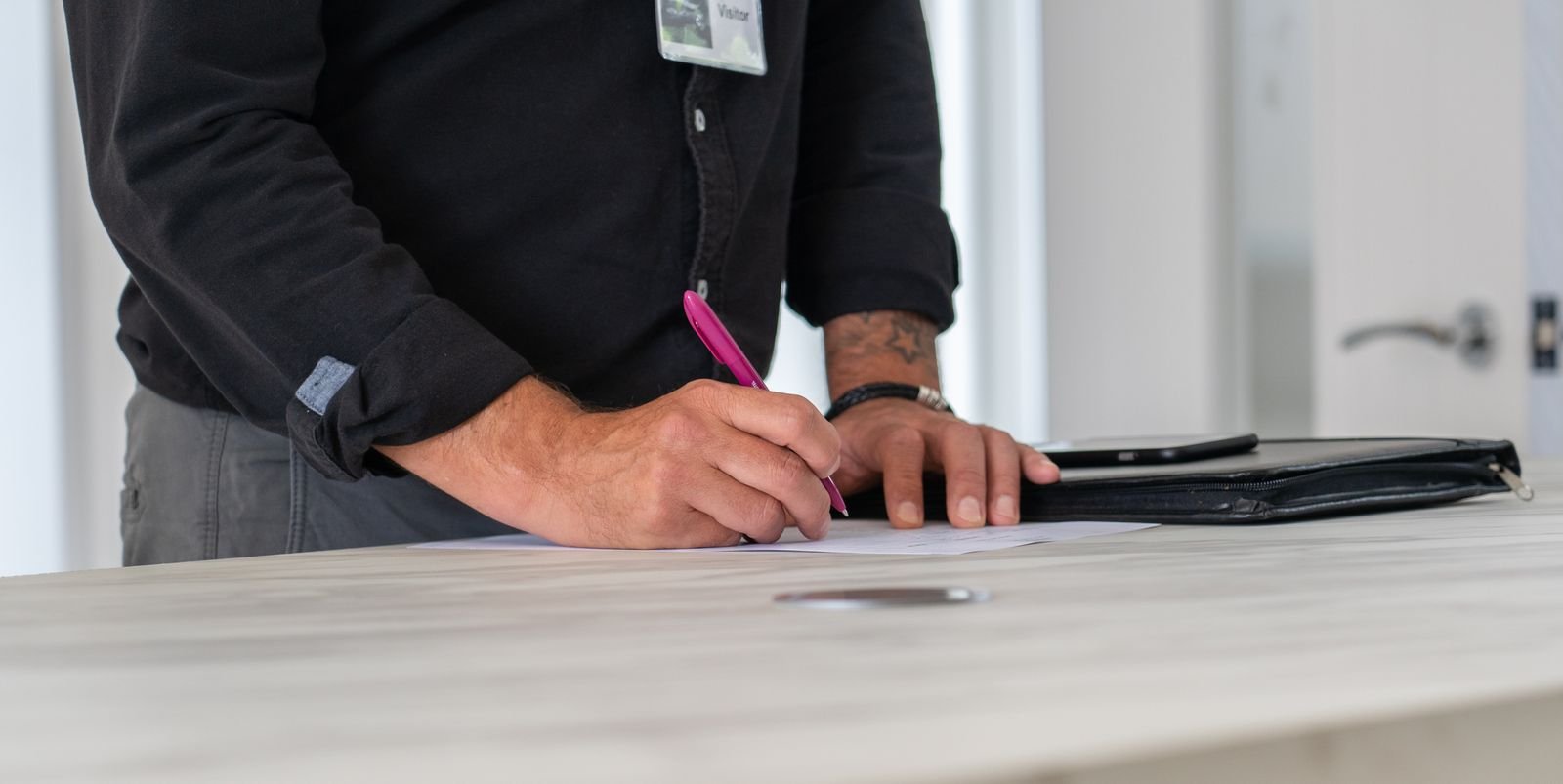 Businessman signing documents at a modern office desk, representing a UAE salary certificate or NOC letter request