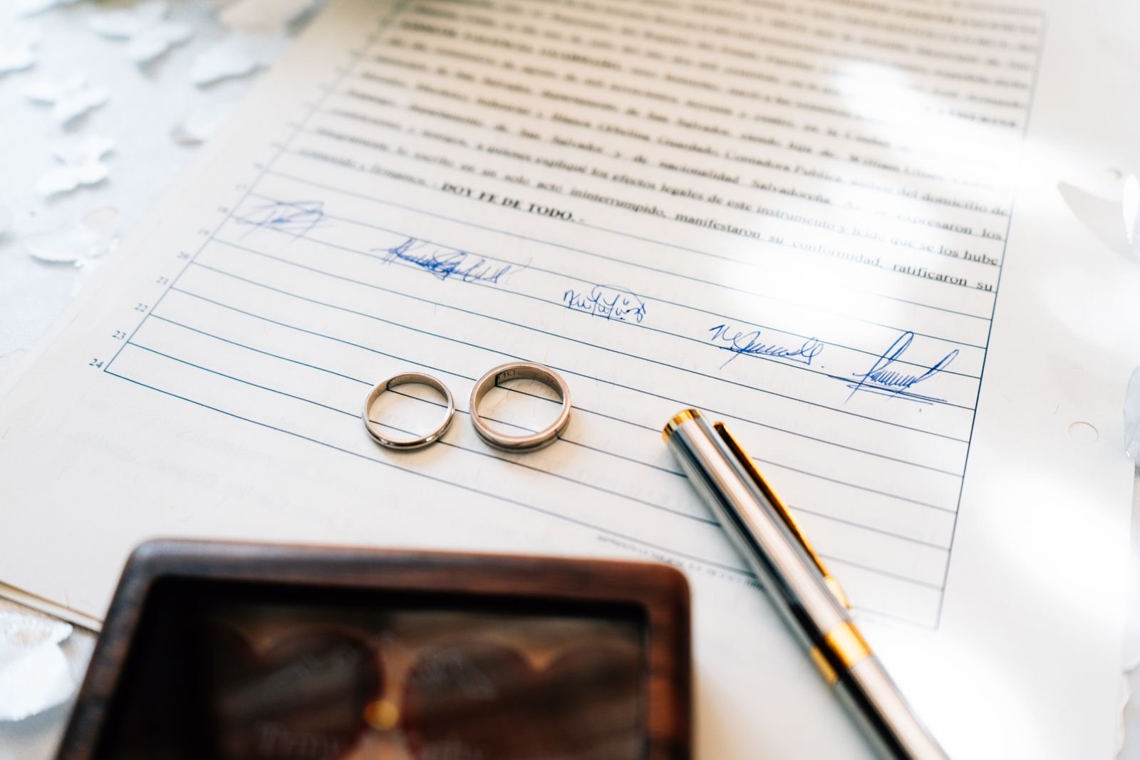 Elegant wedding rings laid on a signed marriage certificate, symbolizing commitment.