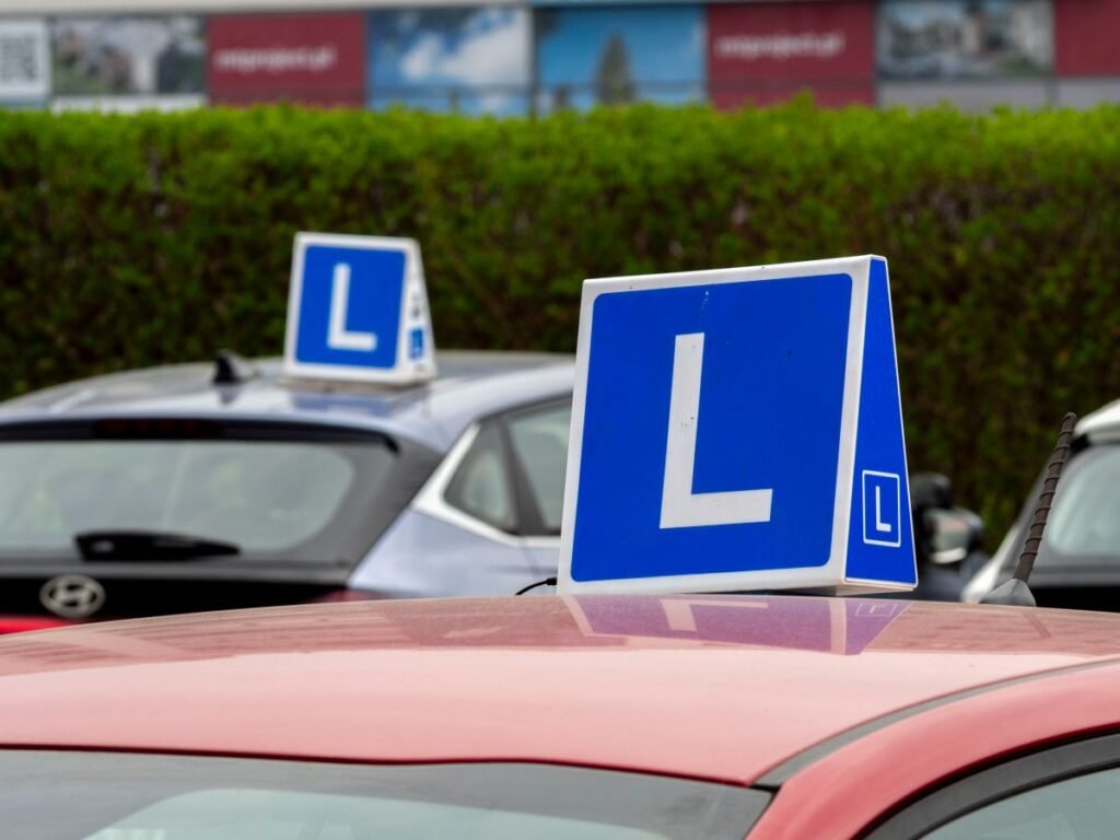 Cars with learning signs parked outdoors at a driving school training area for UAE license conversion