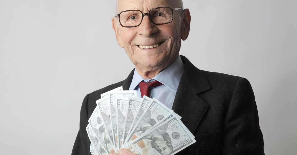 Senior man in a suit holding money, representing UAE Retirement Visa financial eligibility requirements