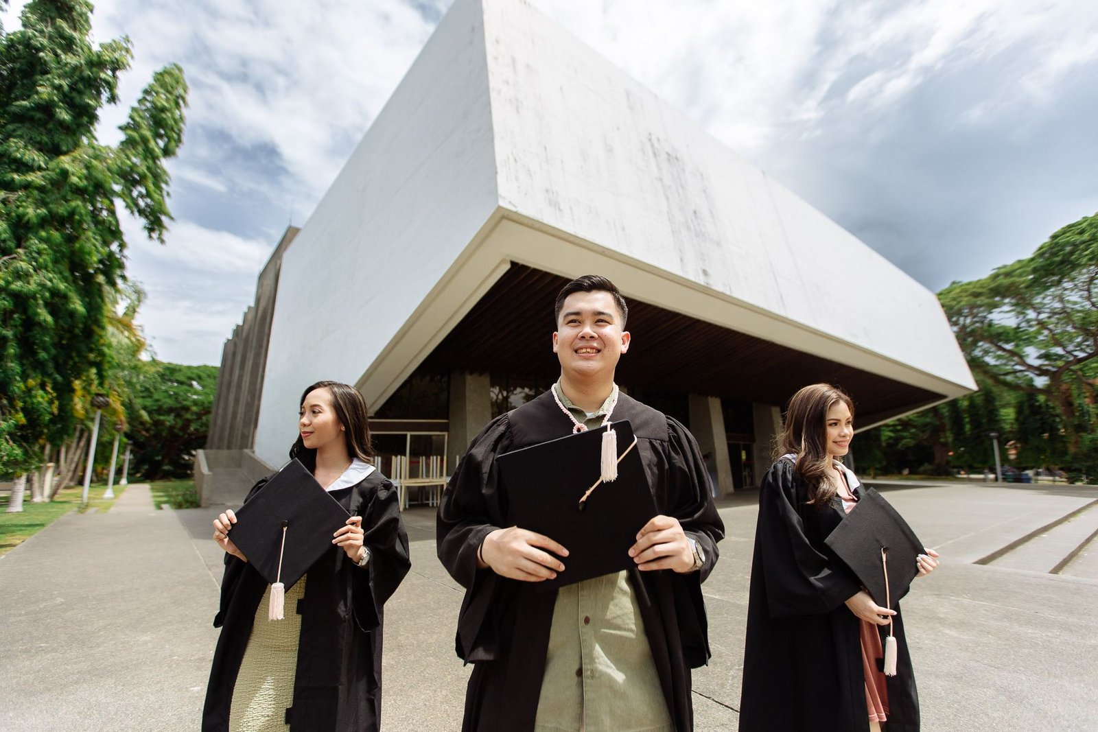 University graduates in gowns holding diplomas outside a campus building, representing the UAE student visa process