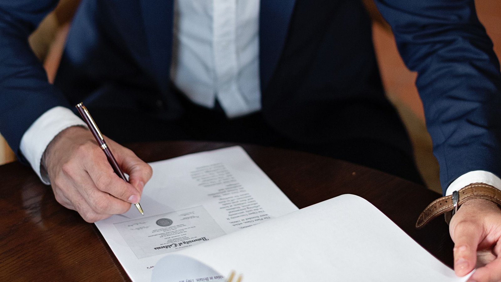 A person signing a bank document, representing settling a bounced cheque in the UAE