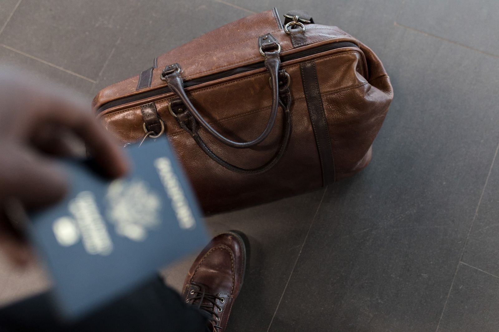 Passport in a leather bag at an airport, representing a UAE resident travelling abroad
