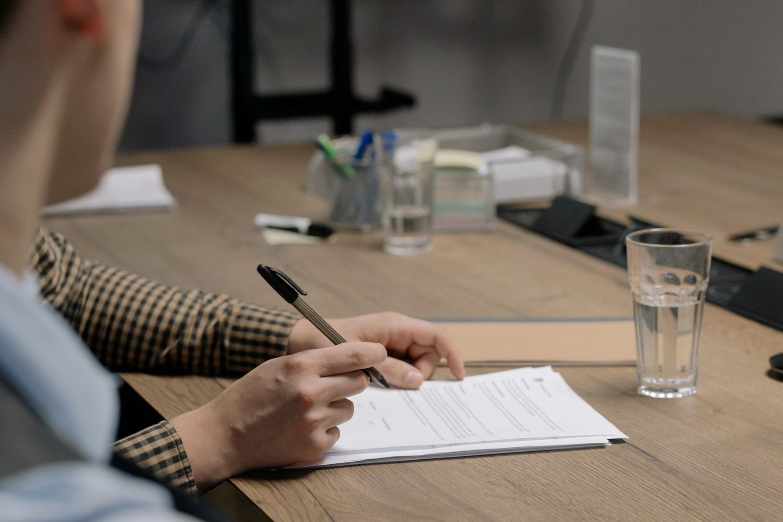 Person signing a business document at a wooden desk, representing amending a Dubai business licence