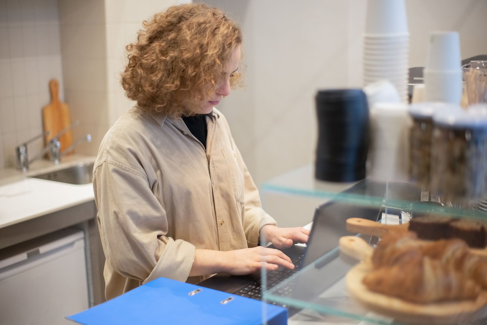 Young woman working behind a cafe counter with pastries in the foreground