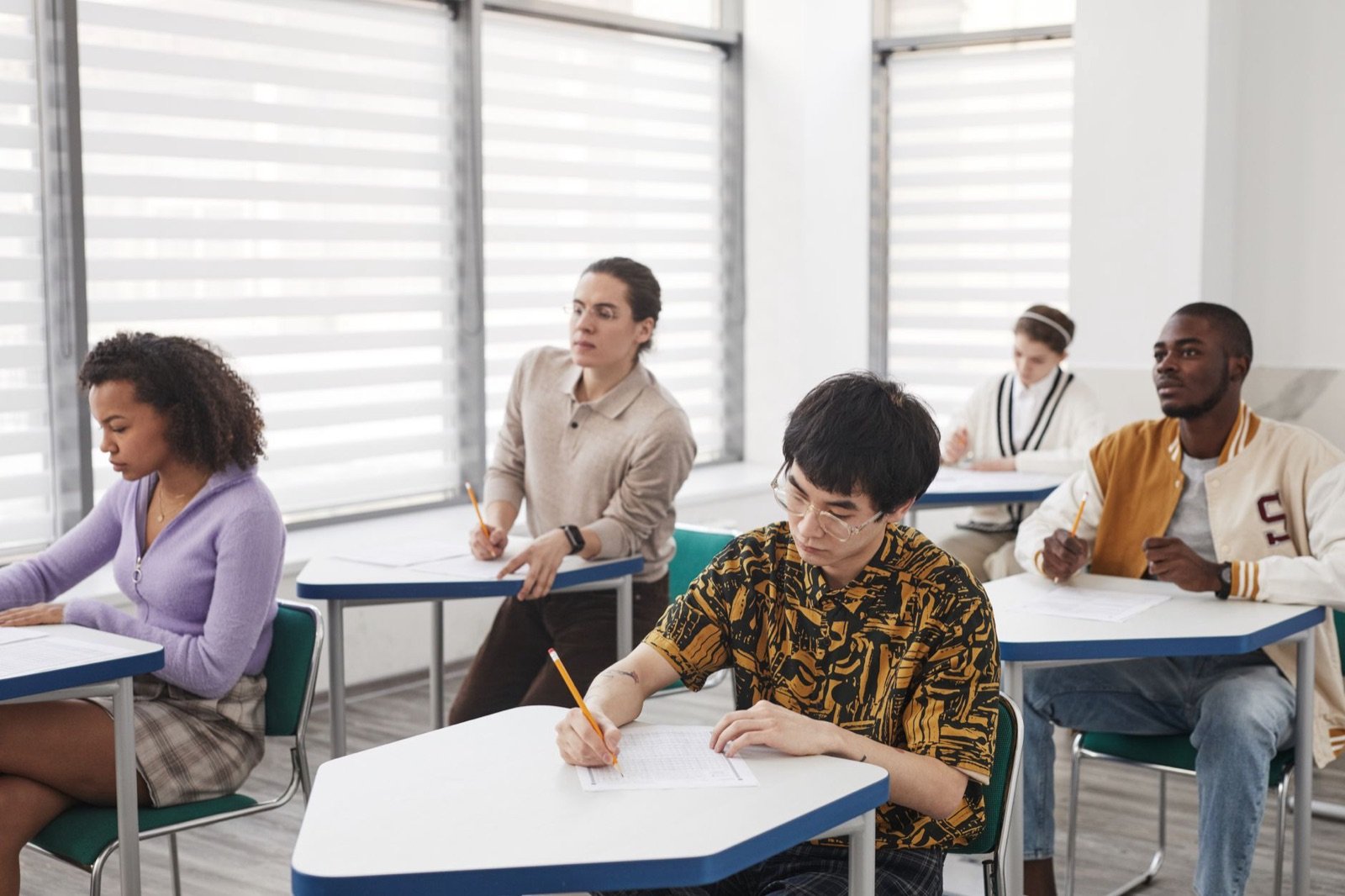 Students writing exam papers in a classroom, illustrating study and exam leave for UAE employees