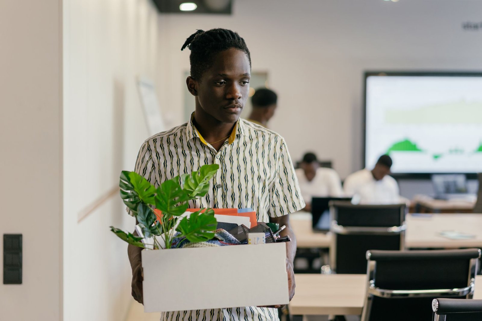 Employee leaving the office carrying a box of belongings after resigning, illustrating the UAE resignation and notice period