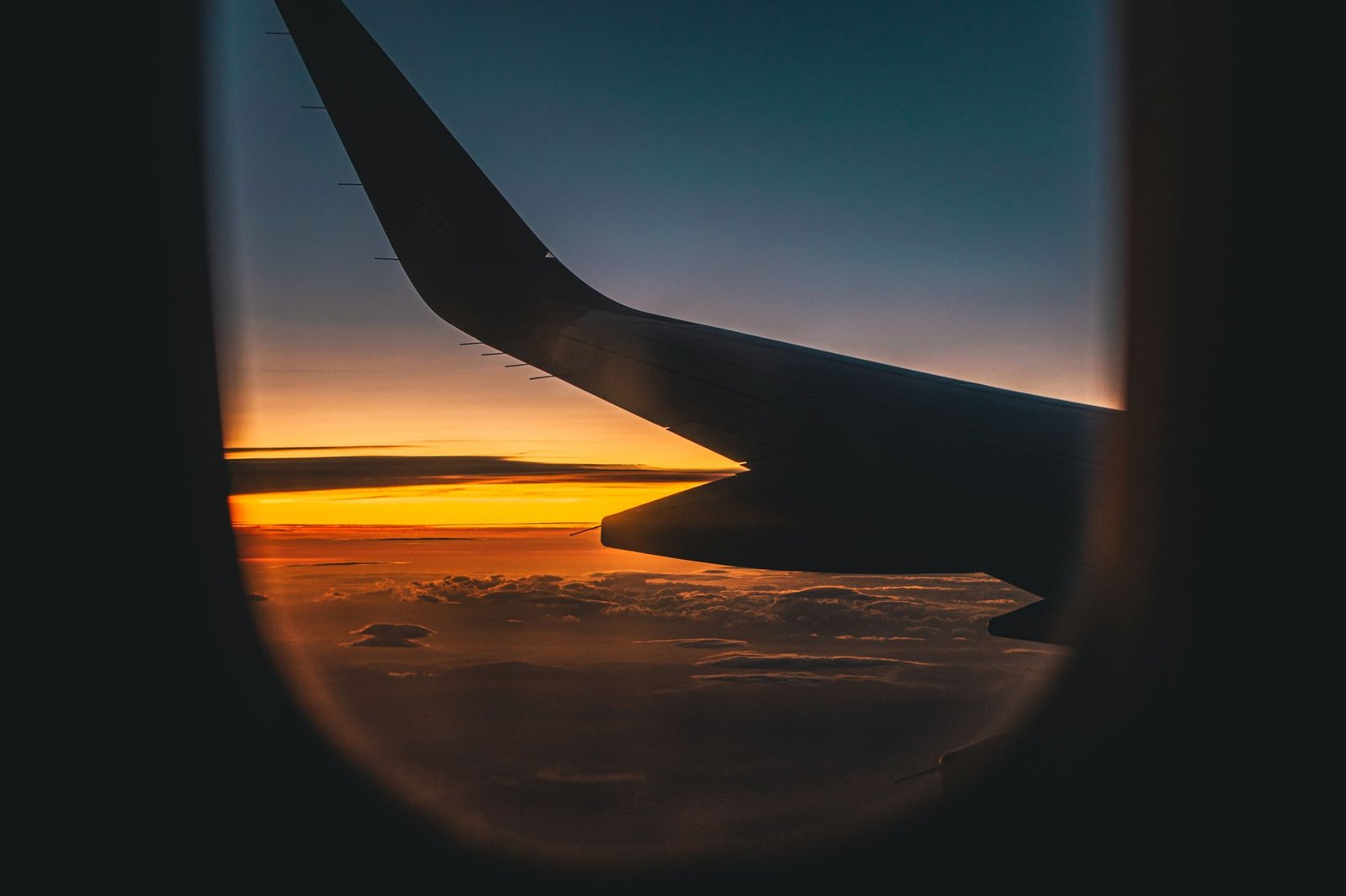 Airplane wing against a sunset sky seen from a passenger window