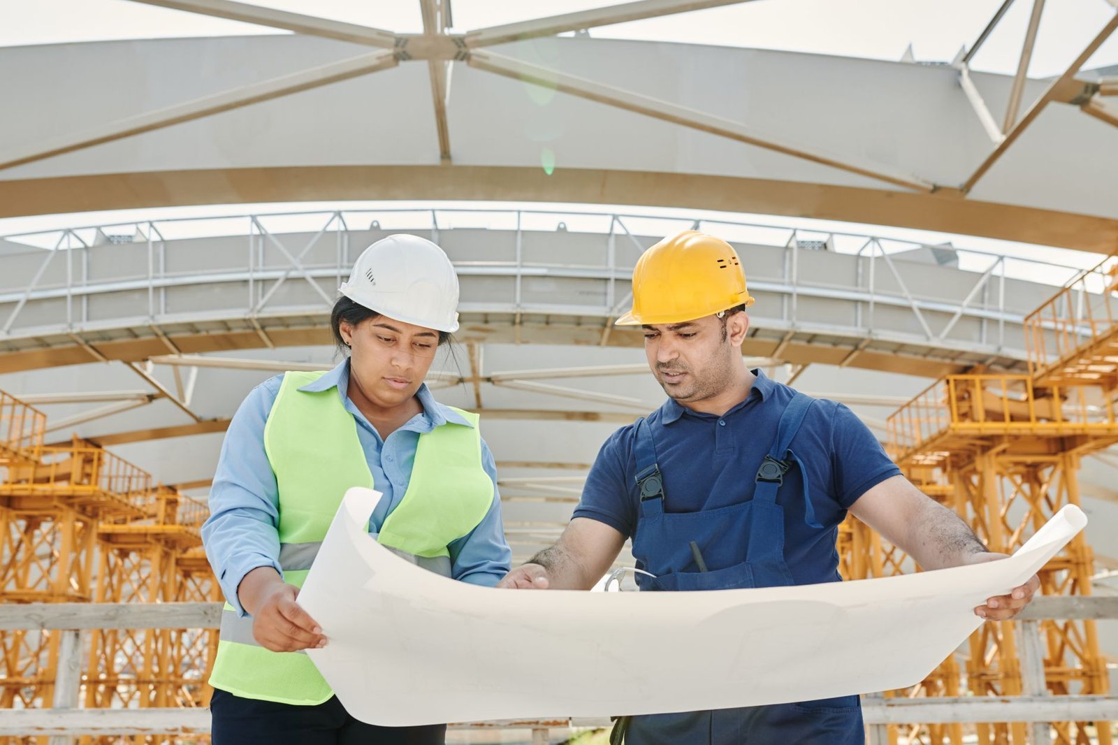 Two construction workers in safety helmets reviewing site plans, illustrating workplace safety and work injury rights in the UAE