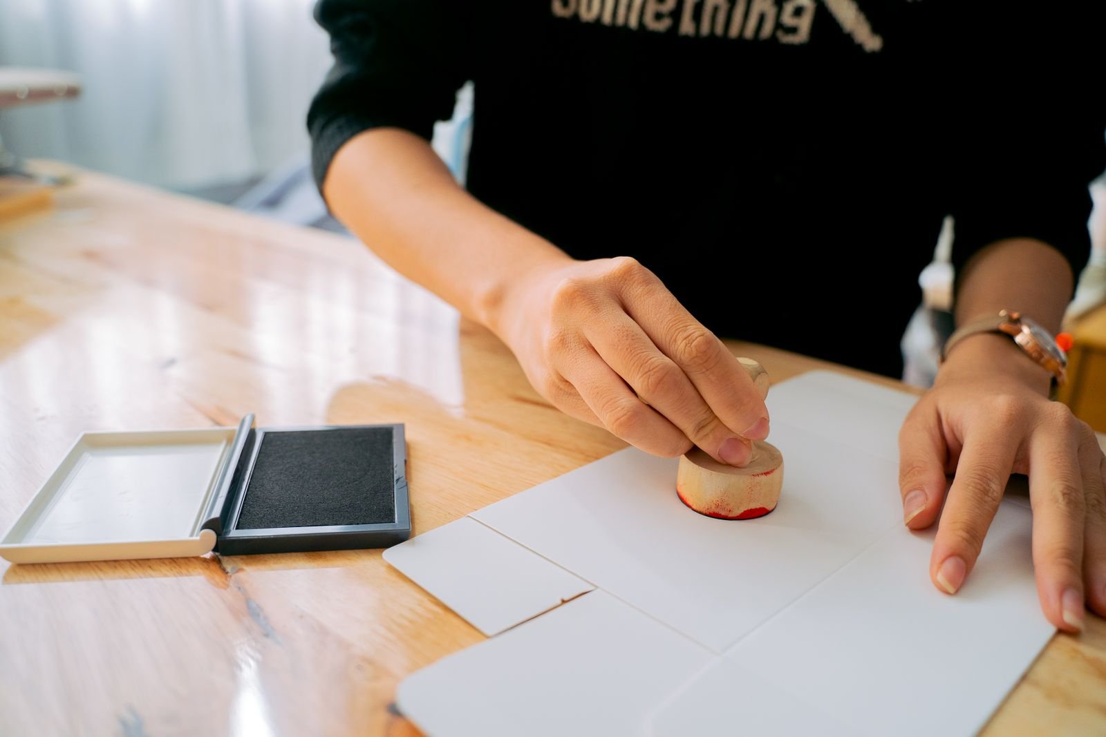 Close-up of hands stamping an official document on a wooden desk, illustrating certified legal translation and stamping in the UAE